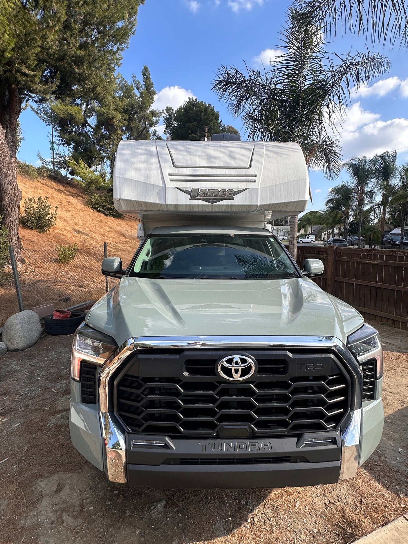A light green Toyota Tundra pickup truck with a Lance truck camper mounted on its bed, available for RV rental.