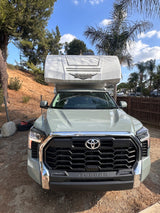 A light green Toyota Tundra pickup truck with a Lance truck camper mounted on its bed, available for RV rental.
