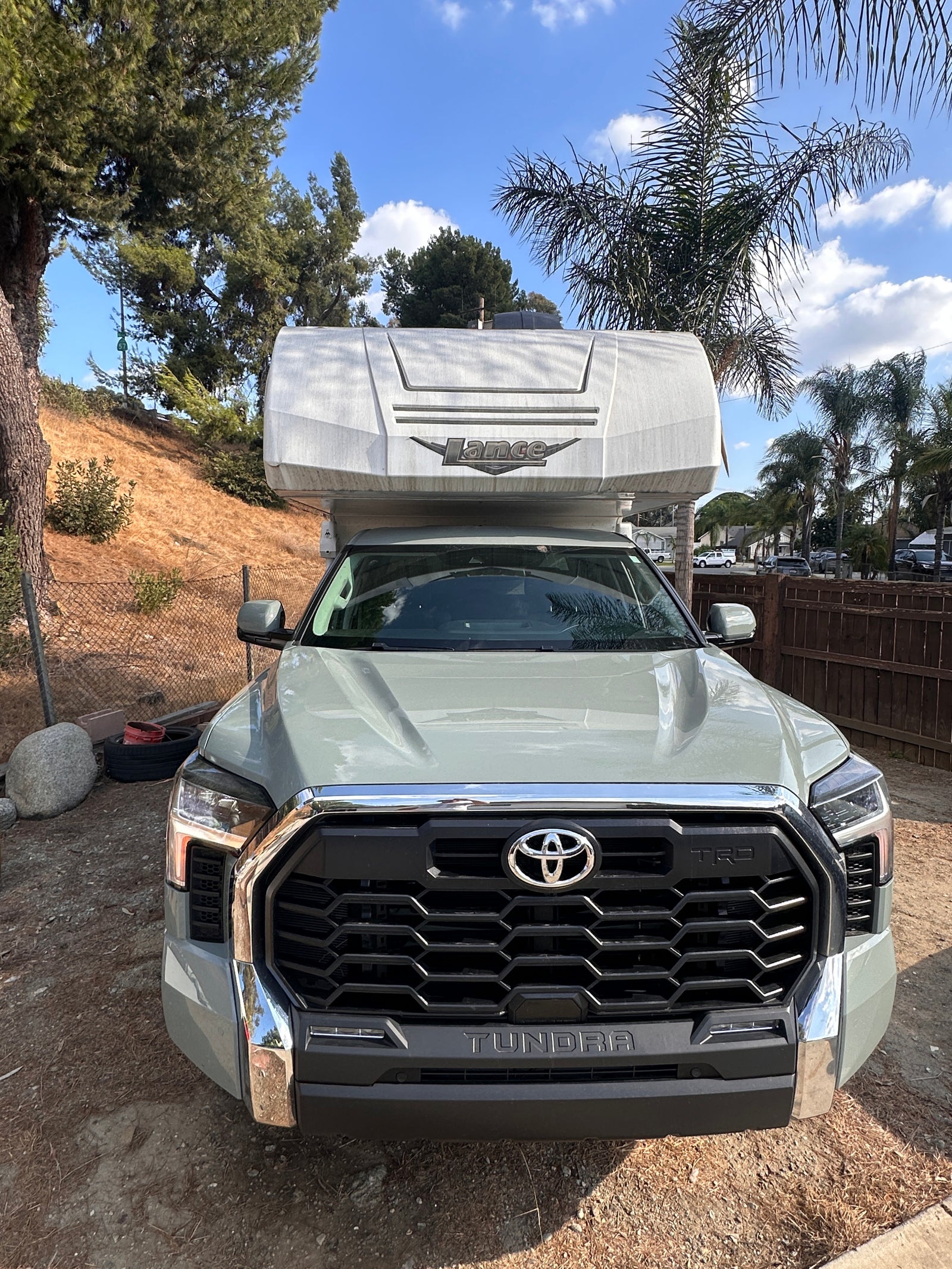 A light green Toyota Tundra pickup truck with a Lance truck camper mounted on its bed, available for RV rental.