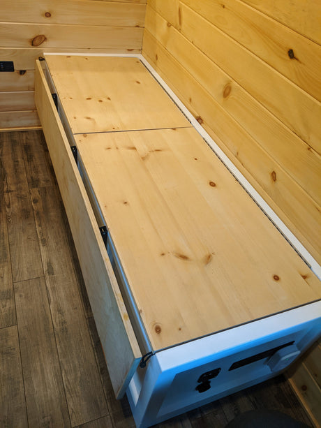 RV rental: Ingenious wood bed/storage bench with hinged panels for compact living, maximizing interior space.