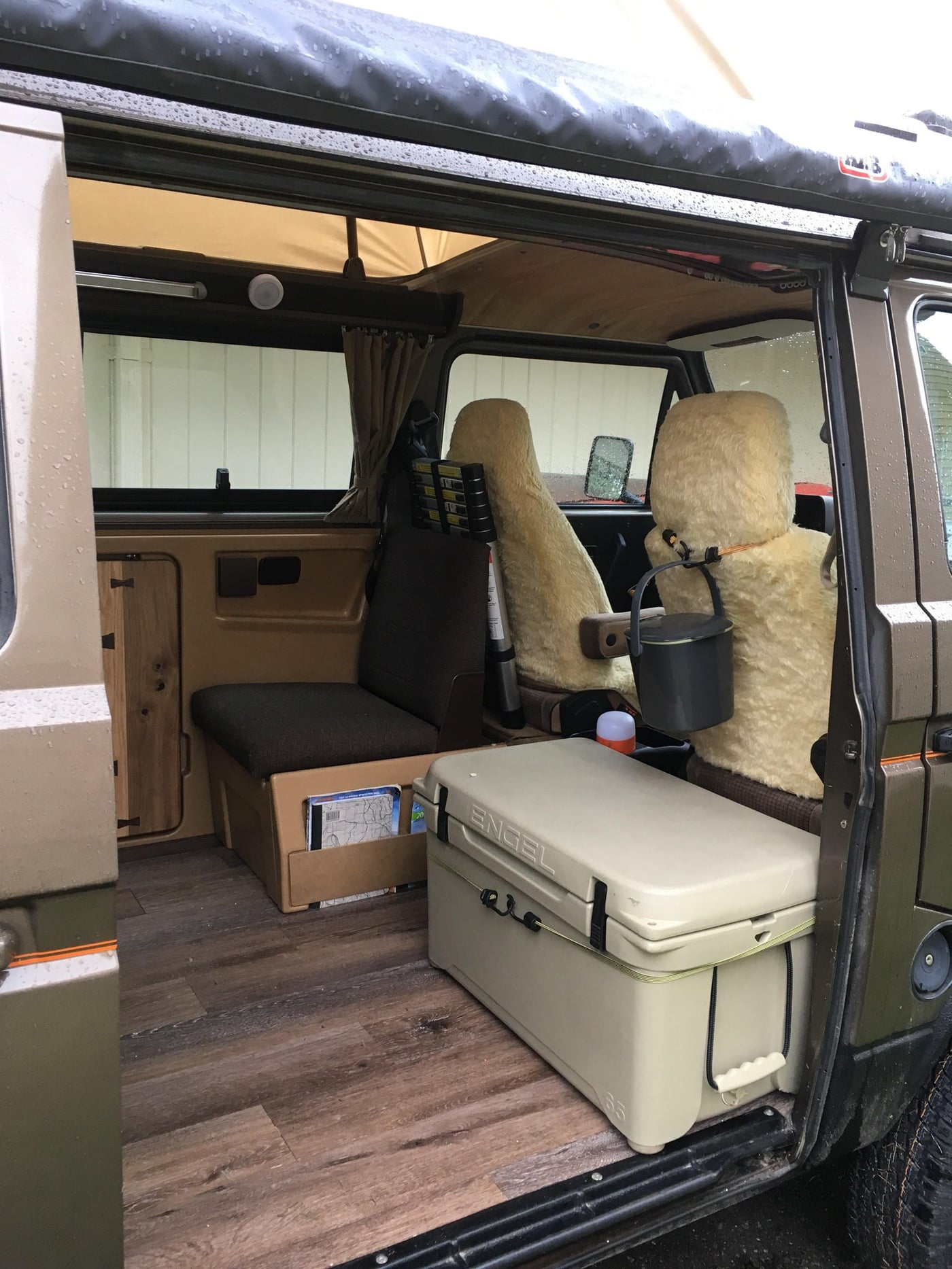  and wood flooring. Ready for comfort!|Brown VW Westfalia pop-top camper van with PNW decal. An ideal rv rental for outdoor adventures.|Interior of a brown camper van featuring wood floors — photo 4