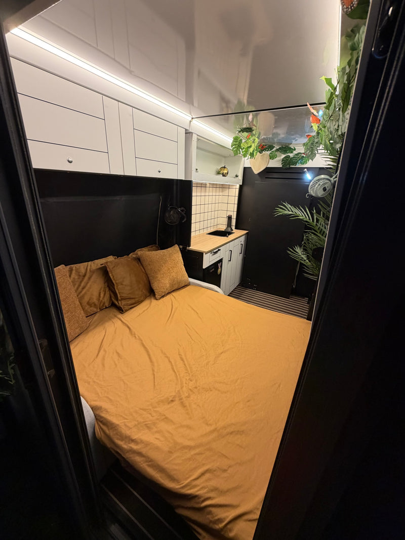 Step inside this stylish RV rental, boasting a comfy bed, integrated kitchenette, and smart overhead storage. — photo 7