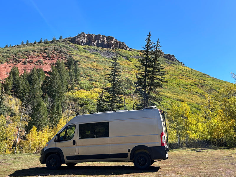An RV rental camper van sits in a vibrant fall mountain landscape under a clear blue sky. — photo 7