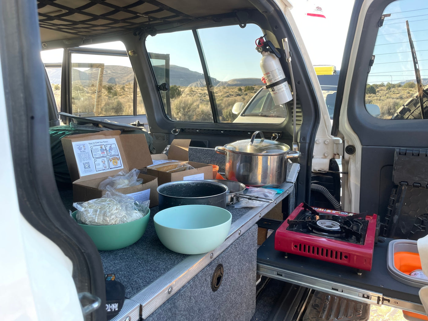RV rental cooking: Ramen prep on a portable stove in a vehicle, perfect for outdoor meals with desert views. — photo 12