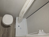 RV rental bathroom: overhead view of a compact toilet, shower, curtain, and soap dispenser.