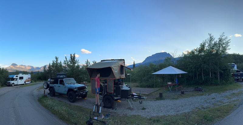 A campsite featuring a Jeep, a trailer with a rooftop tent, and an RV rental. Majestic mountains rise under a clear sky. — photo 7