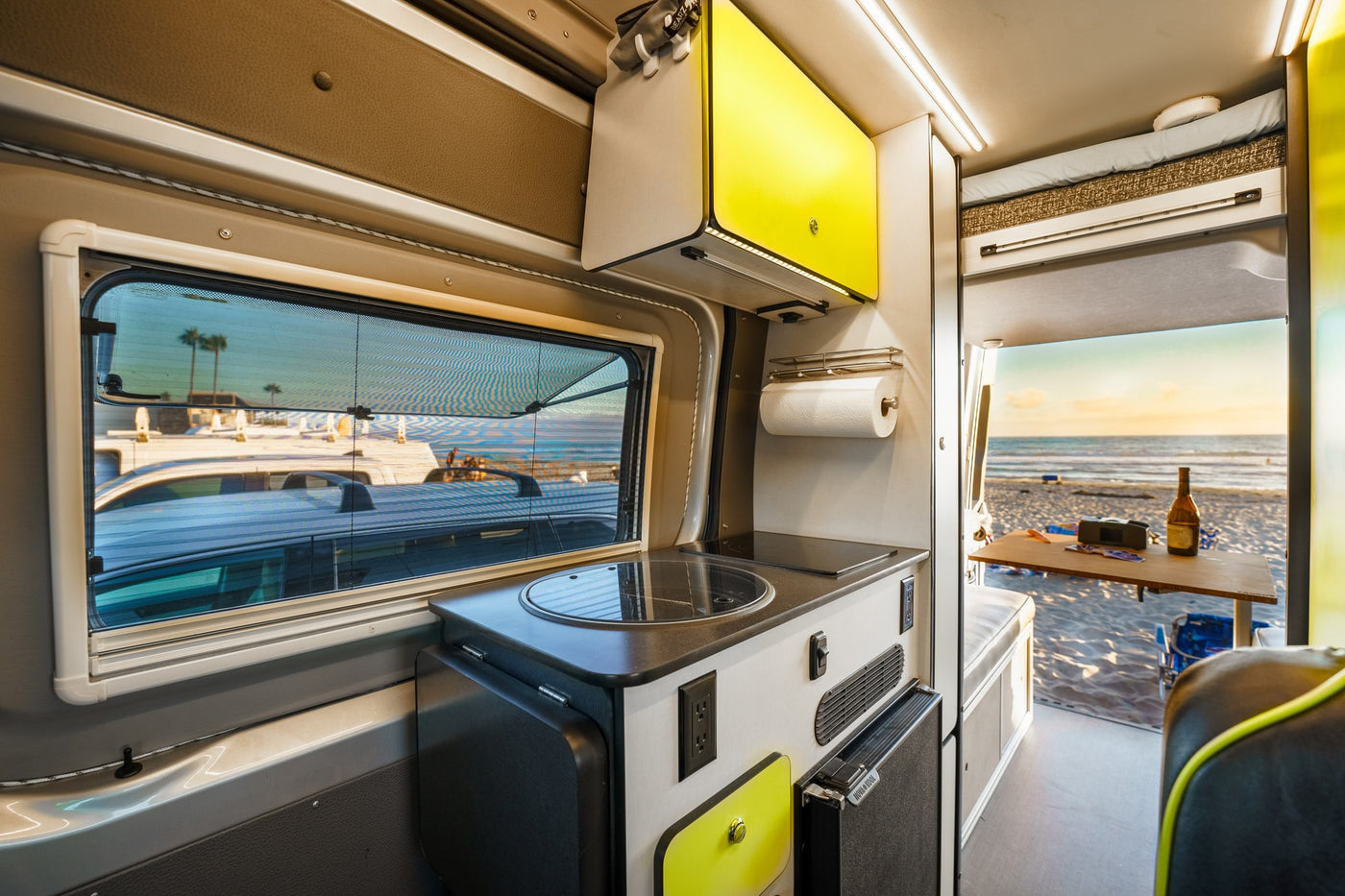 Cozy camper interior with kitchen & window view of a serene beach at sunset. Perfect for your RV rental adventure. — photo 18