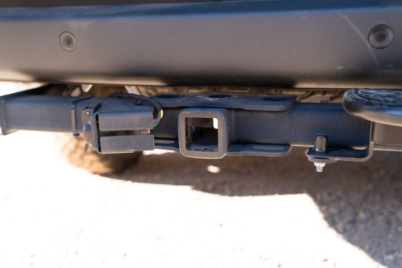 Rear view of an RV rental vehicle, showing its trailer hitch receiver, wiring harness for towing, and parking sensors. — photo 8