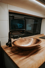 RV rental's inviting kitchen: hammered copper sink, sleek black faucet, and beautiful wood counter.