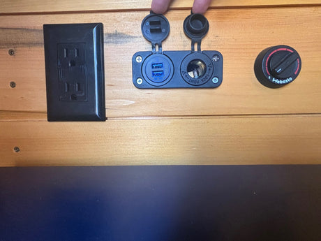 RV rental interior shows an AC outlet, USB/12V charger, and Webasto heater control on wood paneling.