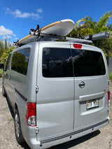 Silver Nissan NV200 van, a versatile RV rental option, with a surfboard ready for beach adventures.