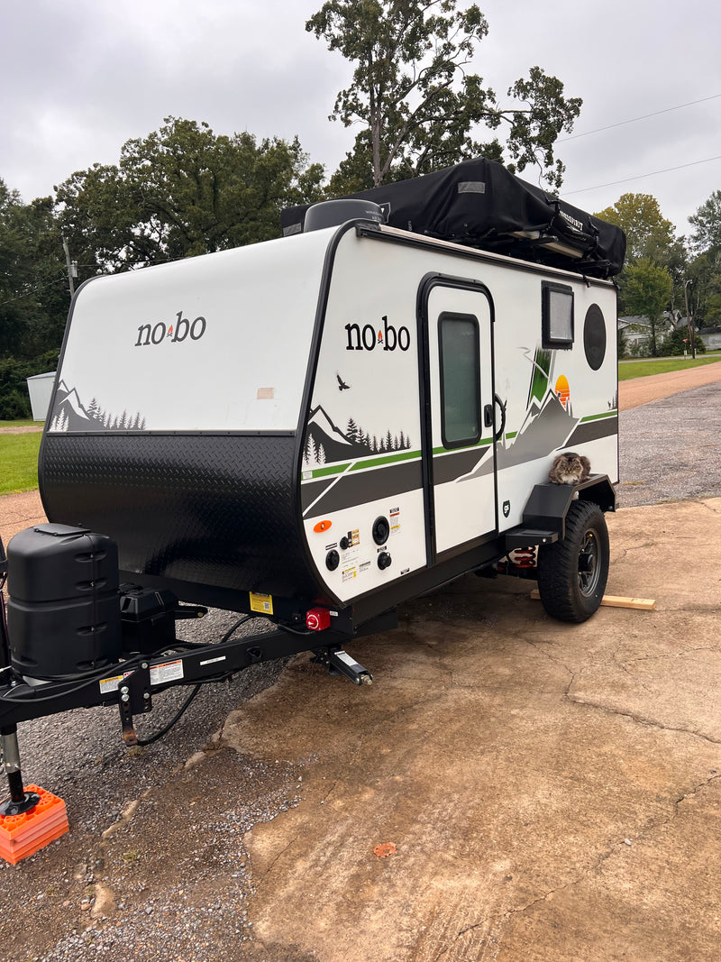RV rental: No Boundaries travel trailer with rooftop tent, mountain graphics, and a long-haired cat on the fender. — photo 2