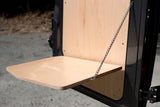 Fold-down plywood table on an RV rental, securely supported by a chain, perfect for convenient outdoor use.