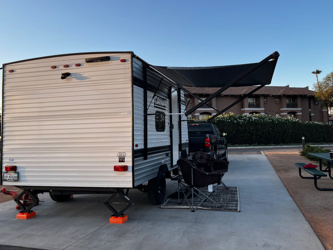  set up with two camping chairs on a rug at sunset/sunrise.|Enjoying an RV rental setup: travel trailer with awning — photo 2