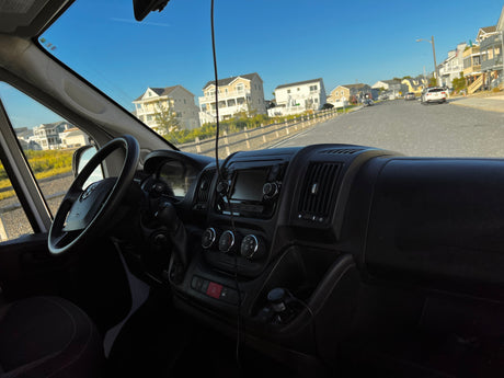 From an RV rental dashboard, a sunny road view of coastal homes and clear sky.
