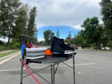 RV rental adventure prep: A portable camping kitchen, featuring a two-burner stove and pump sink, set on a folding table.