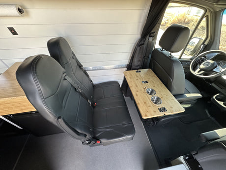 Inside this RV rental: modular black seating, a bamboo table with cupholders, and shiplap walls create a cozy space.