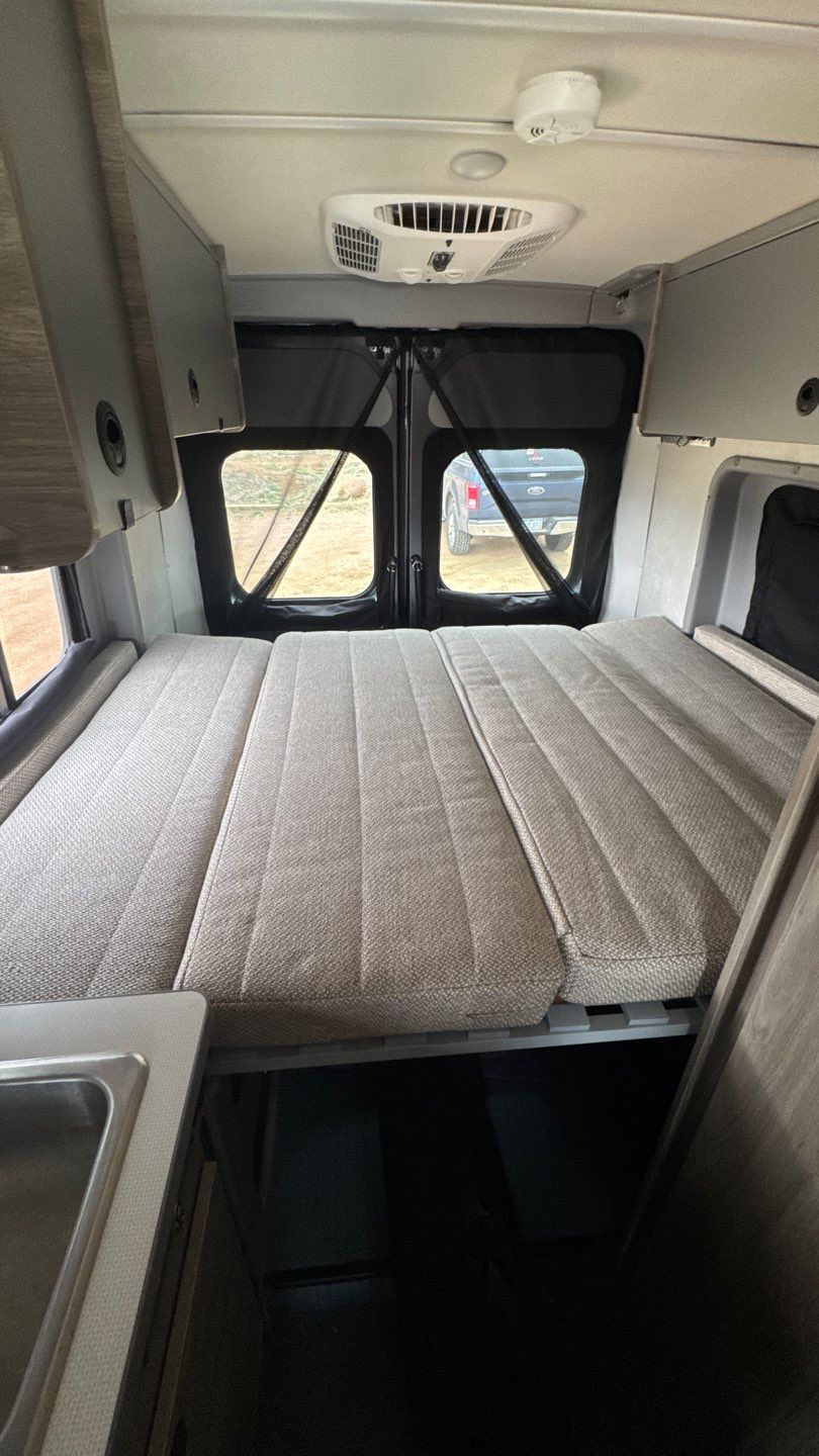 Spacious RV rental interior featuring a versatile bed, overhead AC, and kitchen counter. Your adventure awaits!