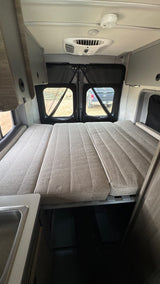 Spacious RV rental interior featuring a versatile bed, overhead AC, and kitchen counter. Your adventure awaits!