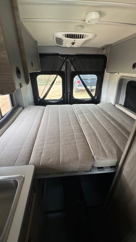 Spacious RV rental interior featuring a versatile bed, overhead AC, and kitchen counter. Your adventure awaits!