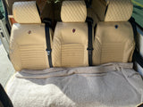 Light-colored, quilted RV rental seats with seatbelts, covered by a soft blanket. Ready for comfortable and stylish travel.