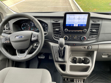 Ford RV rental dashboard and interior. Shows steering wheel with controls, gear shift, and infotainment screen with navigation.
