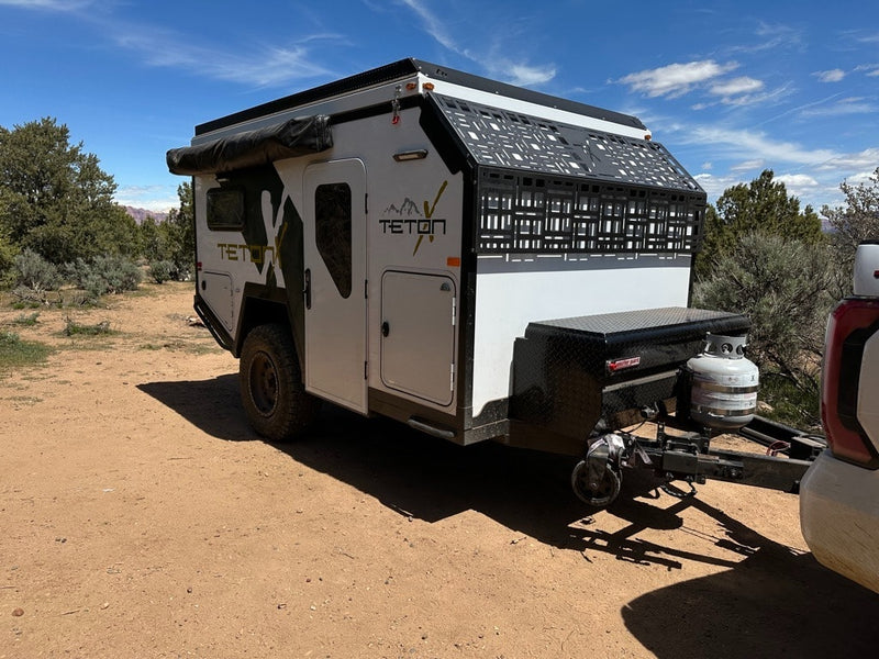 White TetonX overland trailer, an ideal RV rental for off-grid camping, parked on a dirt path under a clear sky. — photo 9