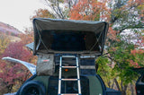 Enjoy autumn with this RV rental setup: a teardrop camper, rooftop tent & ladder amidst vibrant fall foliage. Great for camping!