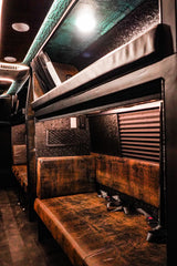 Luxurious custom RV rental interior with distressed brown seating, textured walls, and overhead bunks.