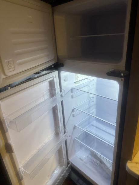 Clean, empty mini-fridge in an RV rental, ready for your trip. Features shelves & door bins.