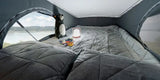 Cozy RV rental sleeping area: a comfortable pop-top bed with a scenic lake view, plush toy, and soft lamp.
