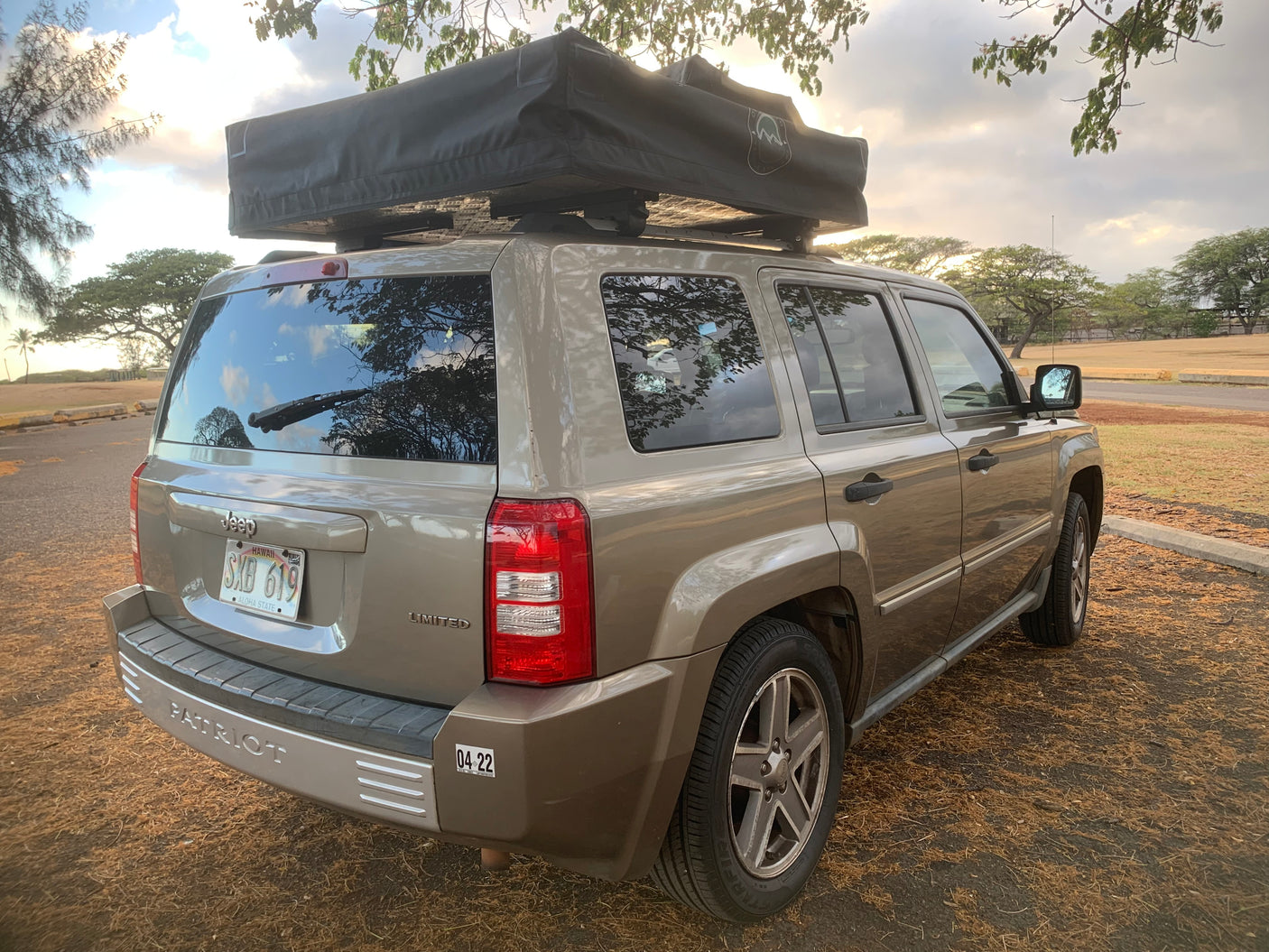 Tan Jeep Patriot with a rooftop tent, an adventurous rv rental alternative for camping and outdoor explorations.