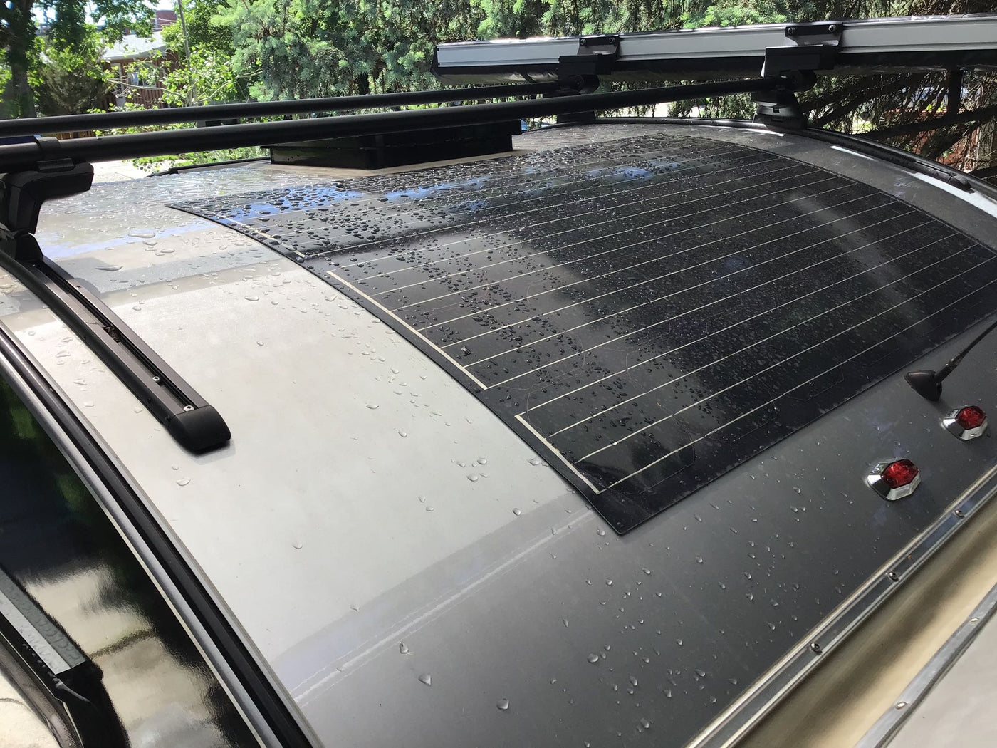 Top view of an RV rental roof showing a wet flexible solar panel, roof racks, and a vent. — photo 10