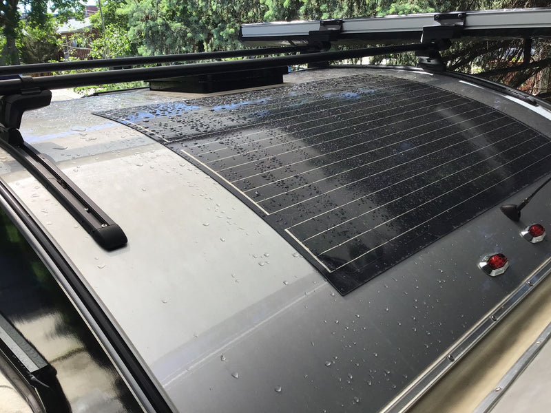 Top view of an RV rental roof showing a wet flexible solar panel, roof racks, and a vent. — photo 10