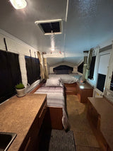 Inside a comfortable RV rental: two beds, tiled floor, and a compact kitchen counter. Ready for adventure!