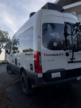 White Mercedes Sprinter RV rental van, "Tranquility," with a bike rack & "California Van Life" decal.