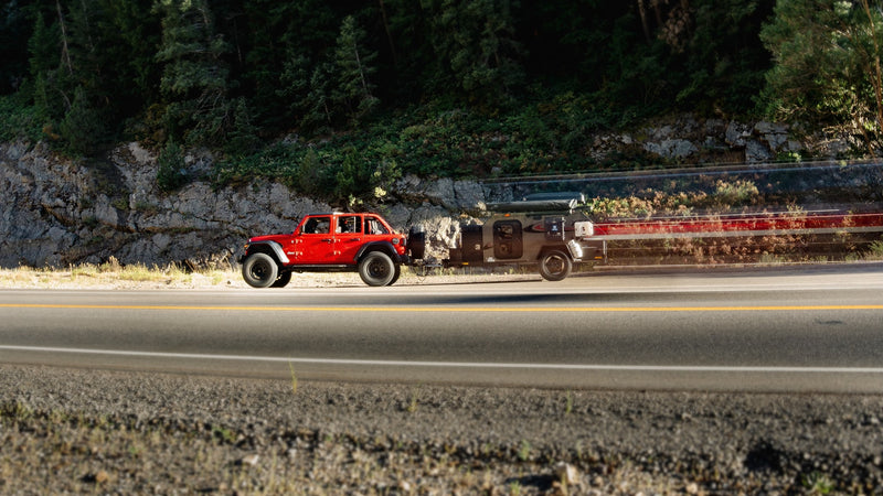 Red Jeep towing a compact RV rental camper on a highway, ideal for outdoor travel. — photo 14