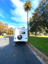Majestic RV rental parked on a tree-lined street with palm trees, ready for adventure.