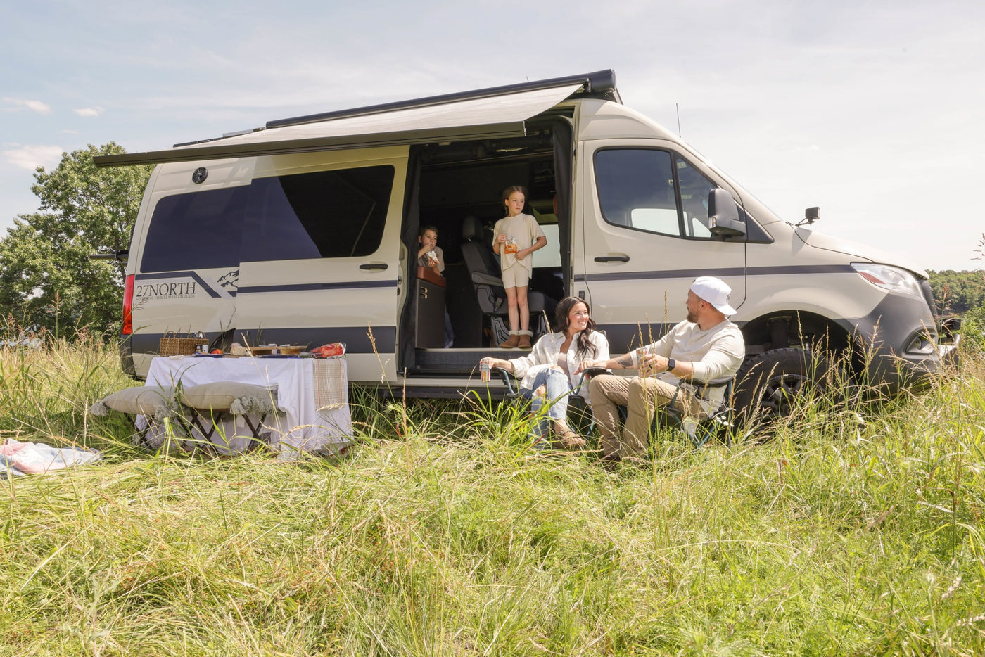 Family picnic with an RV rental. Kids and parents relax by their adventure camper van in a grassy field. — photo 10
