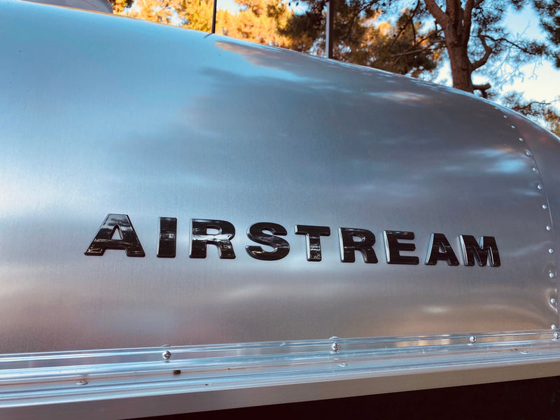  shown with its awning out.|Rear view of a shiny Airstream Bambi travel trailer — photo 5