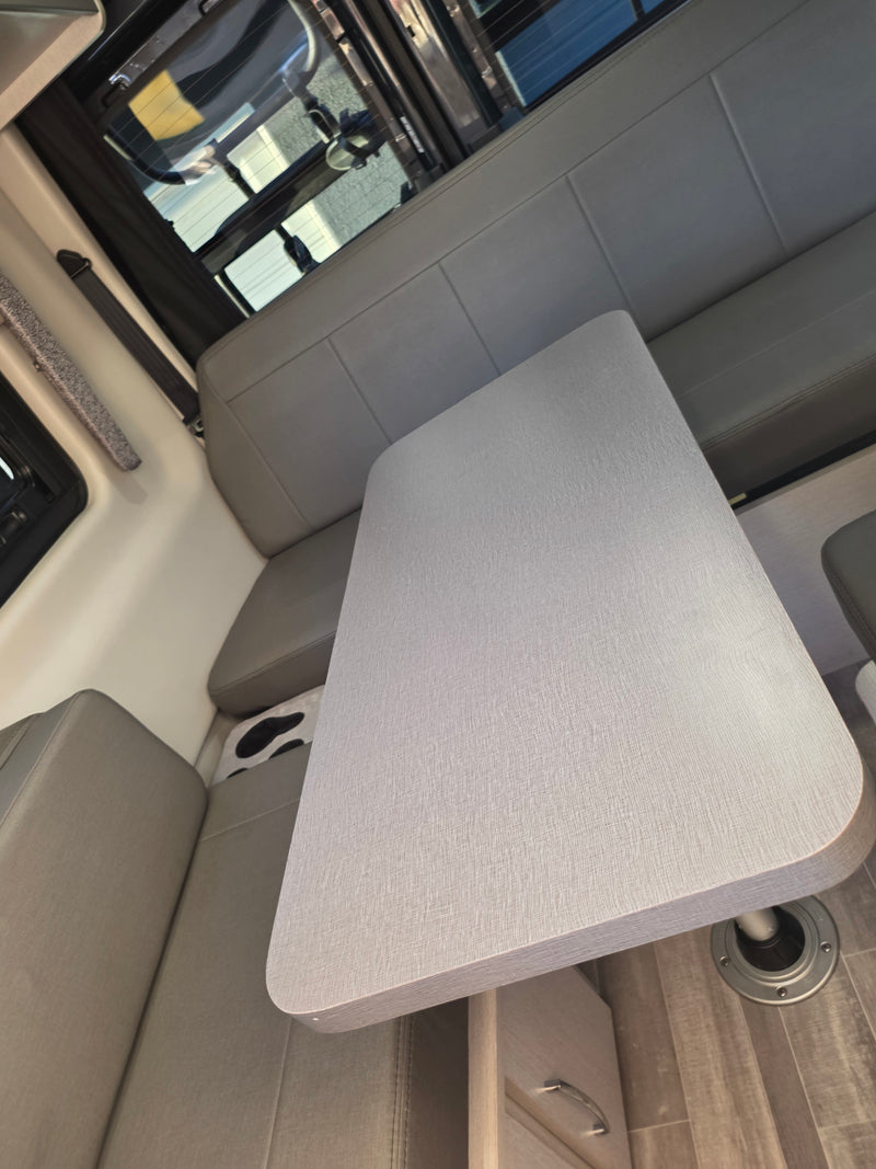 RV rental interior featuring a spacious light gray dining table and comfortable bench seating, ideal for travelers. — photo 6