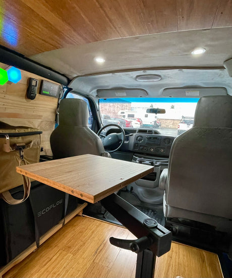 Cozy RV rental camper van interior with a custom wooden table, tech, and visible Ecoflow storage for adventures.