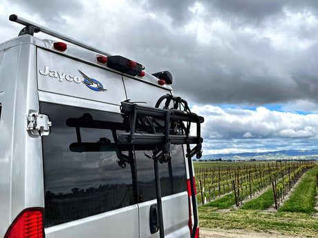 A Jayco rv rental at a vineyard, bike rack ready for scenic road trip exploration under cloudy skies.