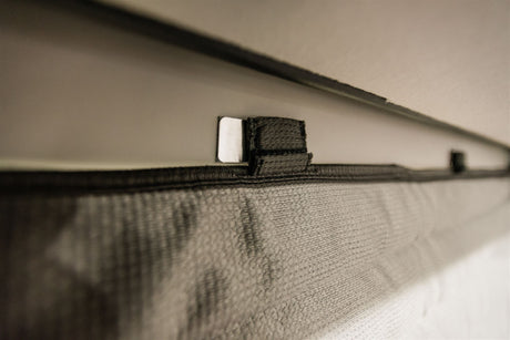 A close-up shows a metallic magnetic clip securing a dark woven screen, likely in an RV rental.