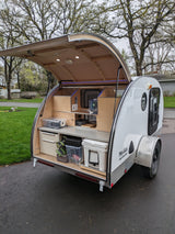 Teardrop camper with its rear galley open, showing a functional kitchen & storage. Great for an RV rental trip!
