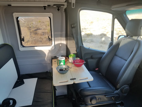RV rental interior with breakfast on a portable table and a scenic desert view from the window.