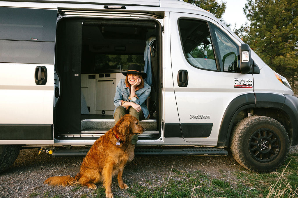  under a vibrant sunset. Ideal for camping trips.|Smiling woman and her dog enjoying an RV rental adventure in their Tofino camper van — photo 2