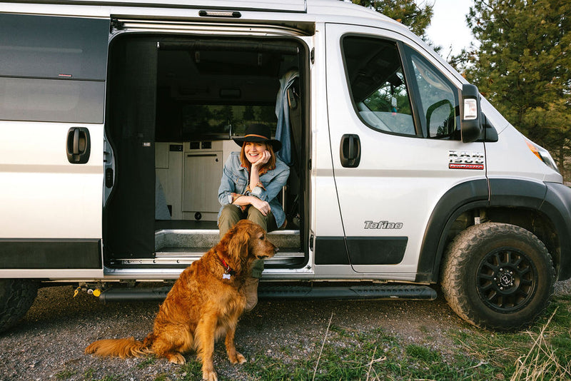  under a vibrant sunset. Ideal for camping trips.|Smiling woman and her dog enjoying an RV rental adventure in their Tofino camper van — photo 2