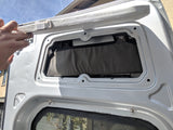 RV rental storage: Hand lifts custom door panel, revealing a mesh pocket for interior organization in a camper van.