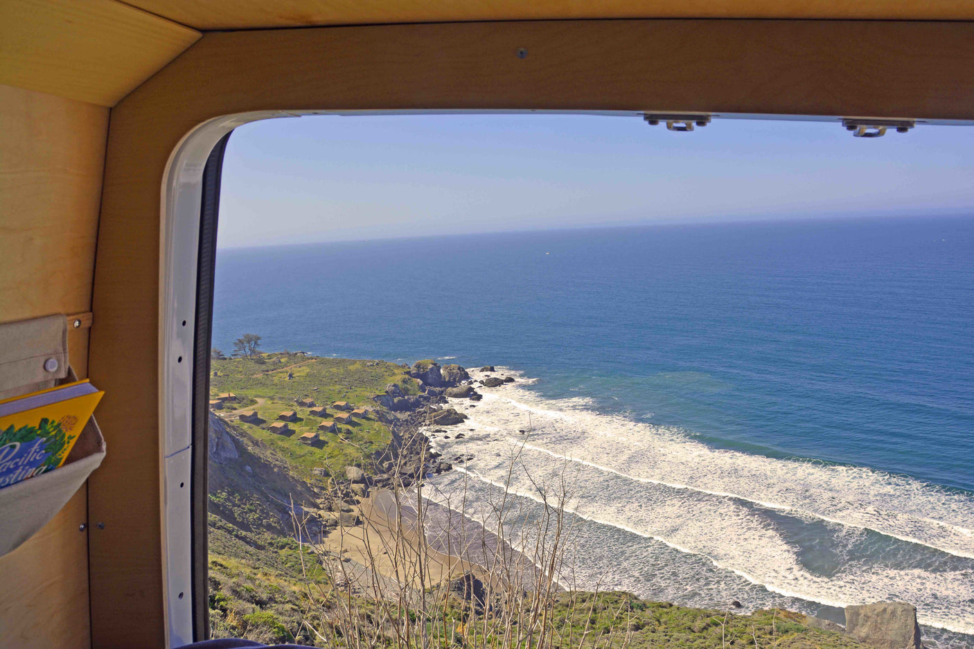 Breathtaking ocean view from an RV rental, featuring coastal cliffs, a sandy beach, and foamy breaking waves. Ideal for travel.